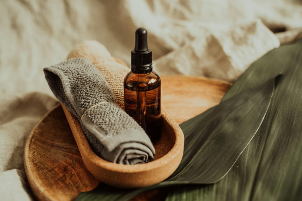 A soothing setup of skincare essentials featuring a dropper bottle, towel, and leafy backdrop, perfect for wellness inspiration.